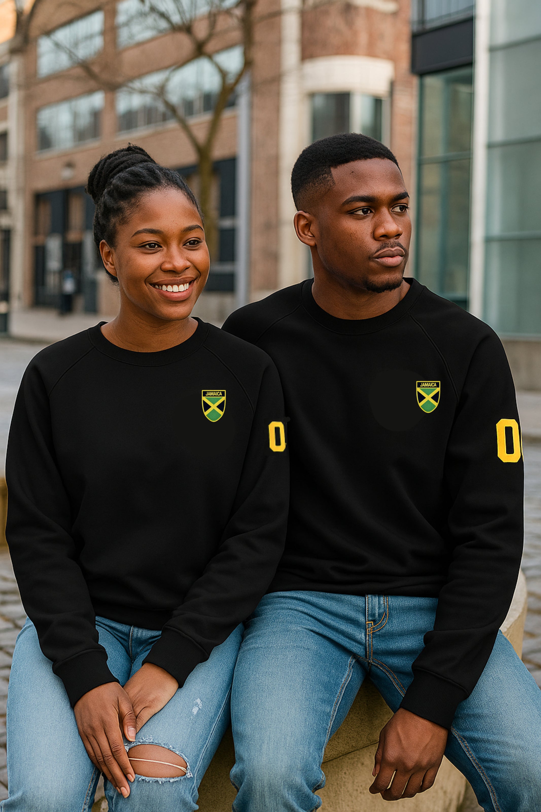 Two people wearing black sweatshirts with yellow logos sitting outdoors.